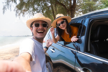 Happy young asian couple taking a selfie while sitting in a convertible car outdoors. Outdoor...