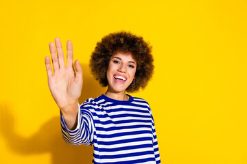 Photo of nice young girl arm wave hi empty space wear striped shirt isolated on yellow color background