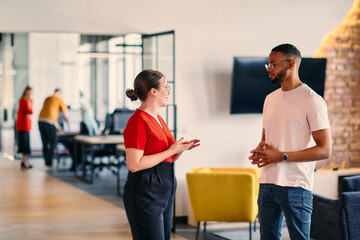 Young business colleagues, including an African American businessman, engage in a conversation about business issues in the hallway of a modern startup coworking center, exemplifying dynamic problem