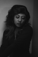 A woman with long hair is sitting in a dark room