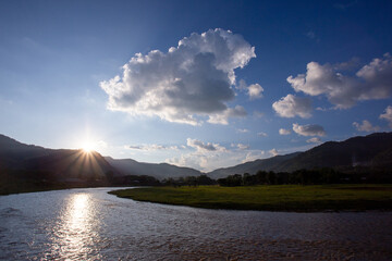 Landscape, river, mountains, green lawn, sunset, bright sky.