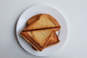 Some toasts or toasted breads, on white plate, isolated on white background, flat lay or top view
