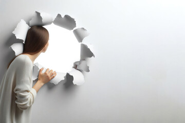person looking through hole in white wall on a white background