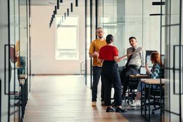 A dynamic group of young entrepreneurs engages in vibrant discussion within a modern glass office...