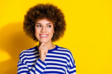 Photo of nice young girl look empty space think wear striped shirt isolated on yellow color background