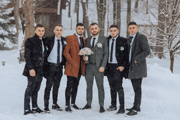 A group of men are posing for a picture in the snow. One of the men is holding a bouquet of flowers