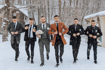 A group of men dressed in suits and ties are walking through the snow. One of the men is holding a...
