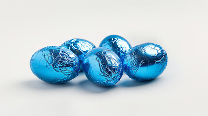 Easter eggs wrapped in blue foil on white background -