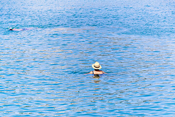 Woman with straw hat relaxing in the water of Peñiscola beach, Castellon, Spain