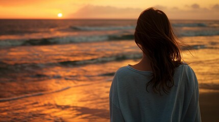 Fototapeta premium Woman watching sunset at the beach, a serene evening seascape.