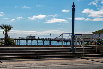 Seaside pier with amusements with blue sky and sunshine. Sandy beach holiday resort. 