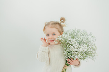 Cute little 3-year-old girl with bouquet of white flowers congratulates her mother on Mother's Day. Happy smiling child. Holiday.