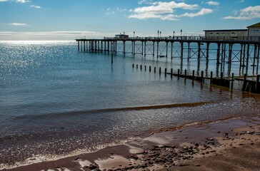 Seaside pier with amusements with blue sky and sunshine. Sandy beach holiday resort. 