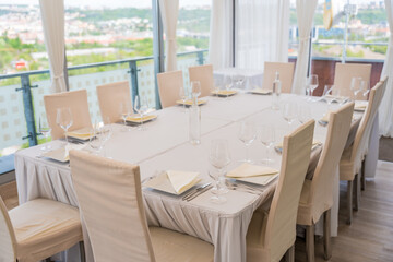 A set table with a beige tablecloth for 12 people. Panoramic view. Decanter of water on the table.
