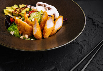 Gourmet fried chicken salad on elegant black plate