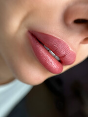 permanent makeup on the lips of a young woman of a delicate peach shade close-up, a girl after a...