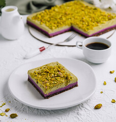 Pistachio cake slice with coffee on a white table