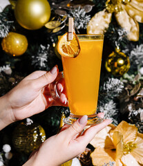 Festive holiday drink in hand by christmas tree