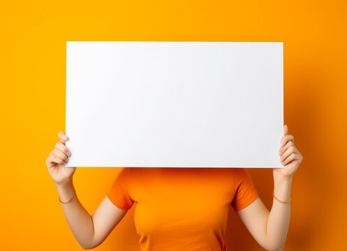 Headless woman holding blank sign, orange background.
