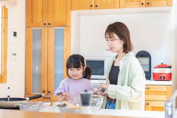 お母さんと一緒に料理をする小さな女の子