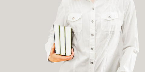 young woman student in white shirt holds a stack of books. horizontal banner, space for text.