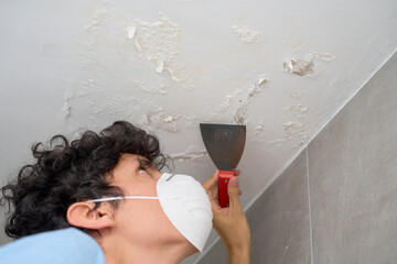 Young man removing moisture and saltpeter from wall and ceiling.