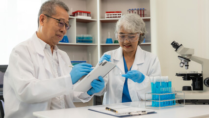 A team of 2 senior Asian scientists perform a thought experiment and a senior male leader prepares...