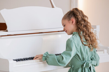 A young girl in green dress is playing the piano