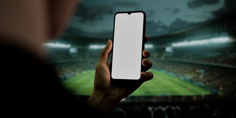 Smartphone in hand at soccer stadium, ideal for sports and betting apps