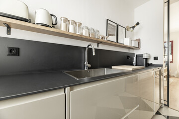 A modern kitchen with glossy lacquered wood furniture, black stone countertop and backsplash of the...