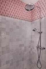 a shower cabin with tiled walls combined with decorative wallpaper and chrome taps