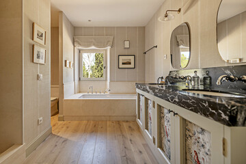 Beautiful and spacious bathroom with black marble countertop with white veins, two mirrors, large...