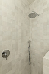 Shower cabin with small gray porcelain tiles, chrome faucets and dies