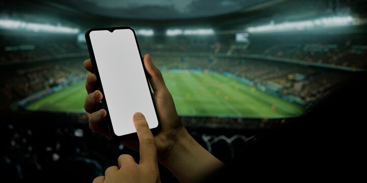 Smartphone in hand at soccer stadium, ideal for sports and betting apps