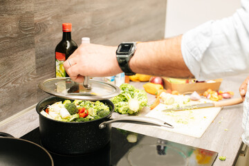 Young man cooking healthy food at home. 
Close up of a man cooking vegetable soup.