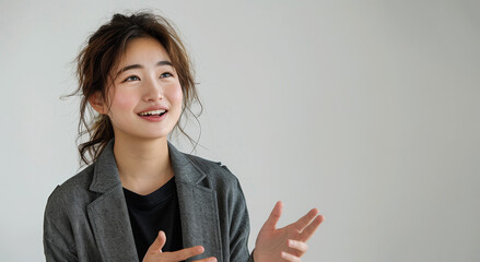 Young Japanese woman in casual attire smiling and gesturing during a friendly conversation