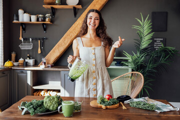 A happy curly-haired girl in a linen sundress is preparing a healthy breakfast. A young smiling...