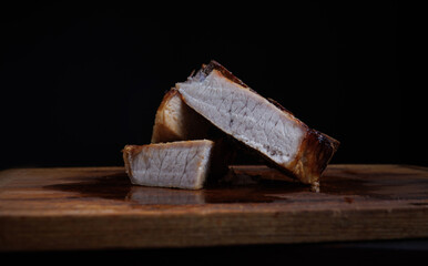 Roasted pork entrecote cut into pieces on a wooden cutting board. Grilled pork entrecote. Pork steak.