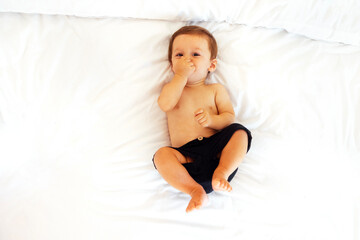 Fototapeta premium The cute baby is laughing and lying on a white sheet on the couch