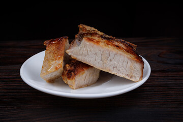 Roasted pork entrecote cut into pieces in a white plate on a wooden cutting board . Grilled pork entrecote. Pork steak.