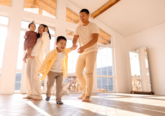 Korean young parents dancing with cute little kids in dining room