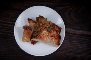 Roasted pork entrecote cut into pieces in a white plate on a wooden cutting board . Grilled pork entrecote. Pork steak.