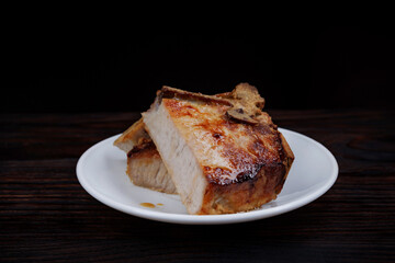 Roasted pork entrecote cut into pieces in a white plate on a wooden cutting board . Grilled pork entrecote. Pork steak.