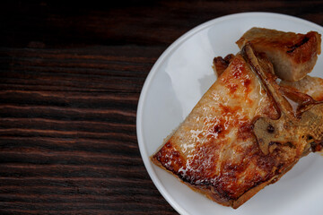 Roasted pork entrecote cut into pieces in a white plate on a wooden cutting board . Grilled pork entrecote. Pork steak.