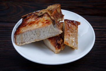 Roasted pork entrecote cut into pieces in a white plate on a wooden cutting board . Grilled pork entrecote. Pork steak.
