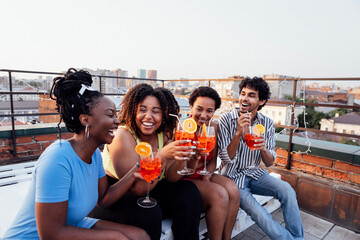 Company of four cheerful friends are enjoying tasty cocktails. Roof party