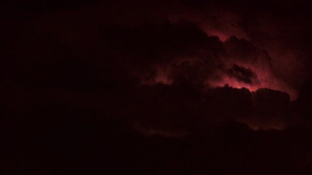 Black thunderclouds are illuminated by flashes of lightning. Stormy weather