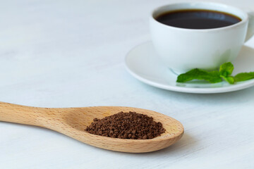 close-up of ground chicory root in wooden spoon and white cup of hot Chicory drink or black coffee isolated on a white background. Healthy herbal drink. coffee substitute. Copy space.