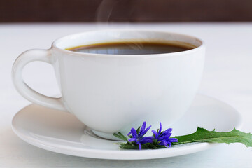 close-up of delicious chicory drink in white Cup decorated chicory flowers. hot and healthy drinks. coffee substitute. copy space.