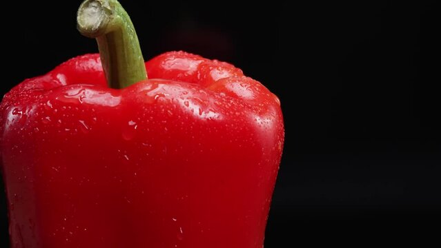 Macrography of a red bell pepper against a sleek black background takes center stage. Each close-up shot meticulously captures the intricate details and textures of the pepper. Close up. Comestible.